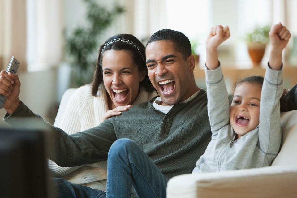 multicultural family watches tv from couch