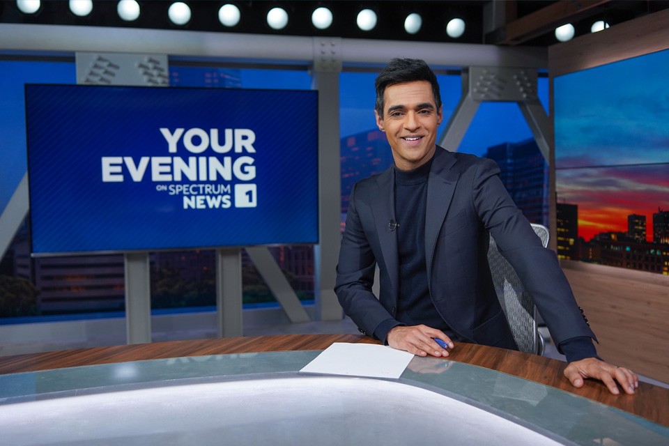 Spectrum News anchor with Evening News on screen